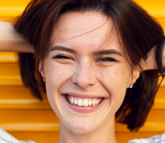 Woman relaxing against a wall with her hands behind her head