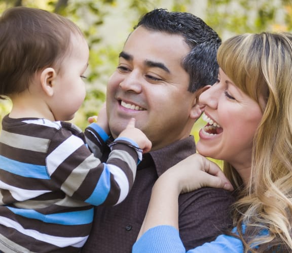 Father and Mother holding their child and smiling at each other