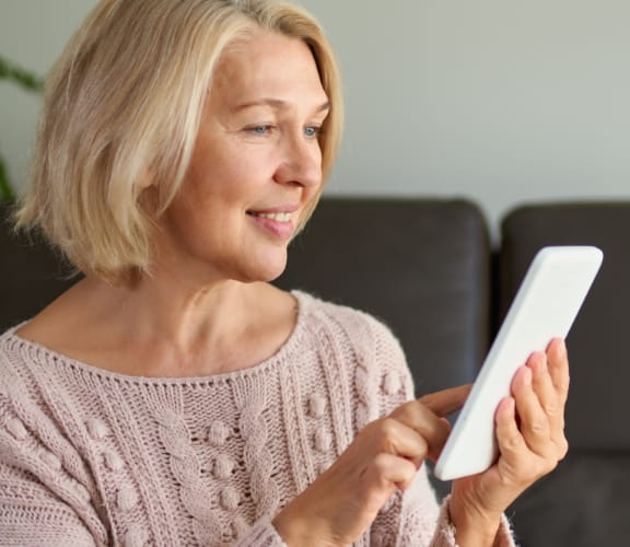 Older woman sitting on the couch and looking at her phone